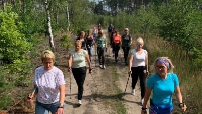 Marsz Nordic Walking. Panie idą przez las.