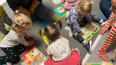 Dzieci przeglądające książki. Siedzą na szarym dywanie w kolorowe motyle.