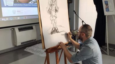 Hubert Ronek rysujący swoją wybraną postać komiksową na sztaludze.