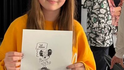 Dziewczyna prezentująca swój rysunek, który naszkicował jej H. Ronek